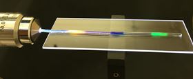 MIT researchers have developed a stretchy optical fiber in which they injected multiple organic dyes (yellow, blue and green regions). In addition to lighting up, the dyes act as a strain sensor, allowing the researchers to quantify where and by how much the fiber has been stretched. Photo courtesy of the researchers.